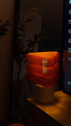 Triangular orange lamp on a dark background with a plant 
