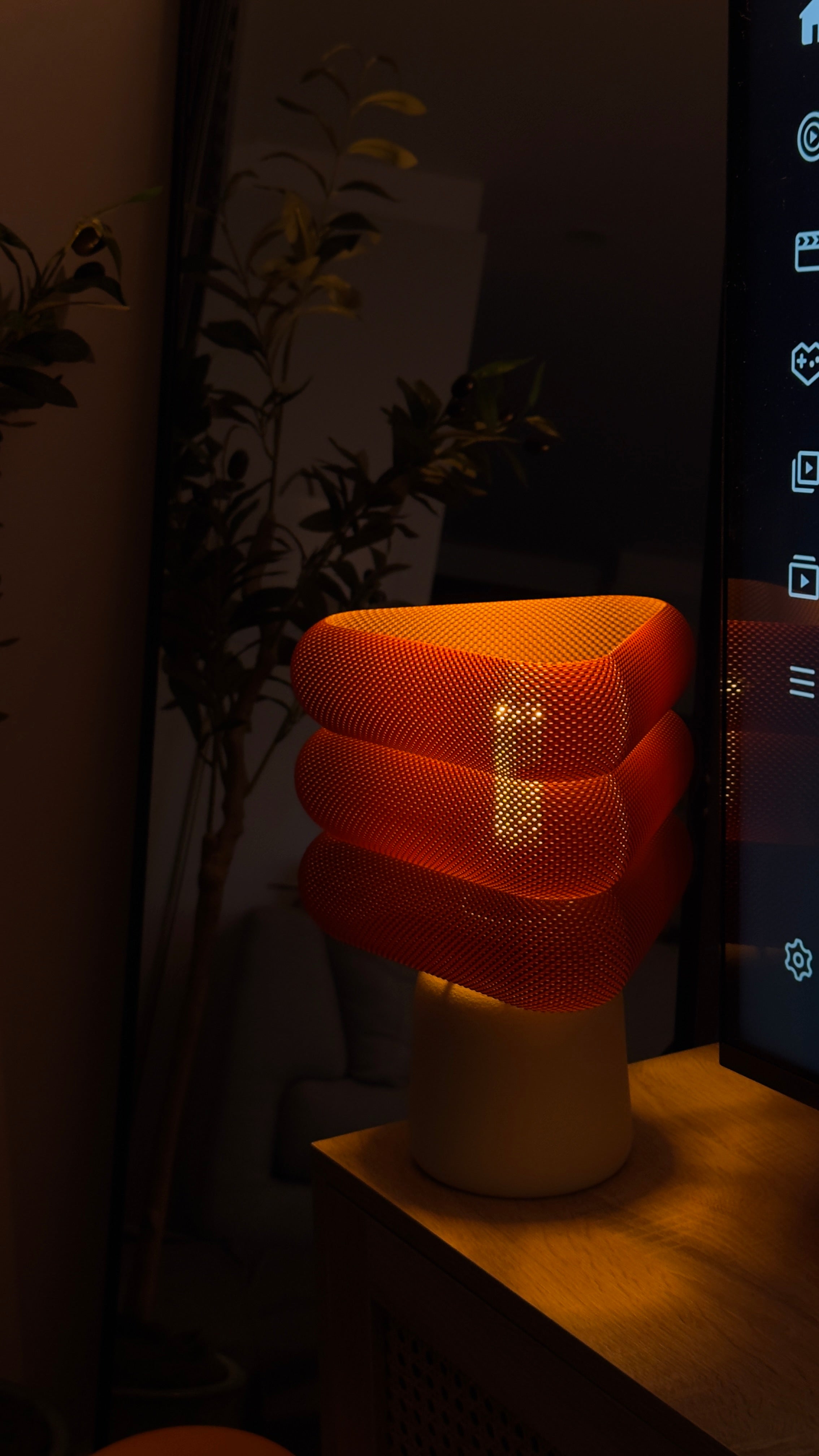 Triangular orange lamp on a dark background with a plant 